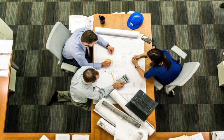 Engineers discussing boat design around a table, planning hull, layout, and structure